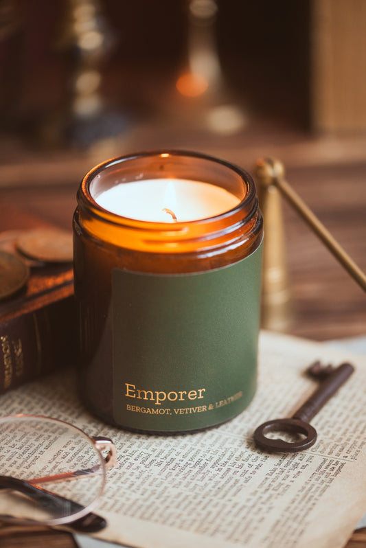 Bergamot, Vetiver & Leather scented soy candle by COSYPLACE CANDLES in a stylish glass jar, showcasing its warm amber glow.